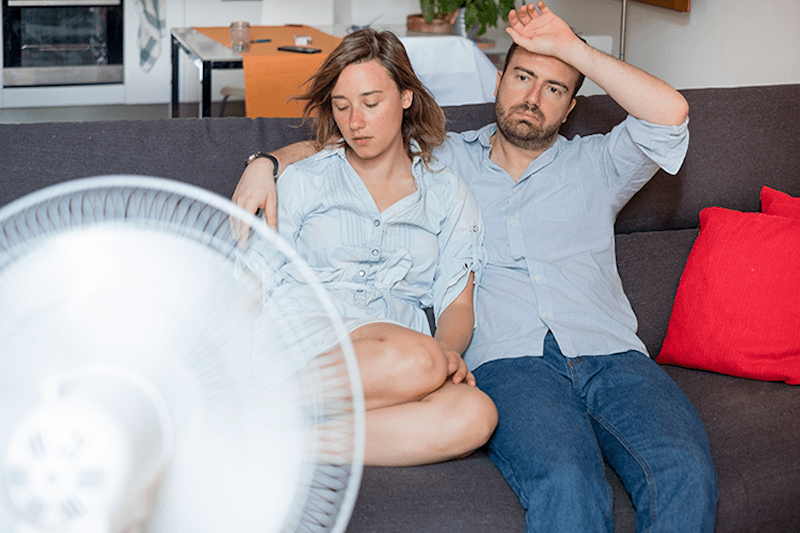 Image of couple sitting on couch in front of fan. What Does Indoor Air Quality Have to Do With Allergies?