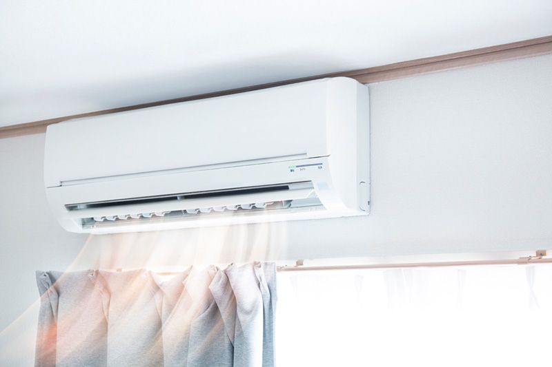 Image of a ductless system on the wall blowing air. Why Ductless Is the Way to Go.