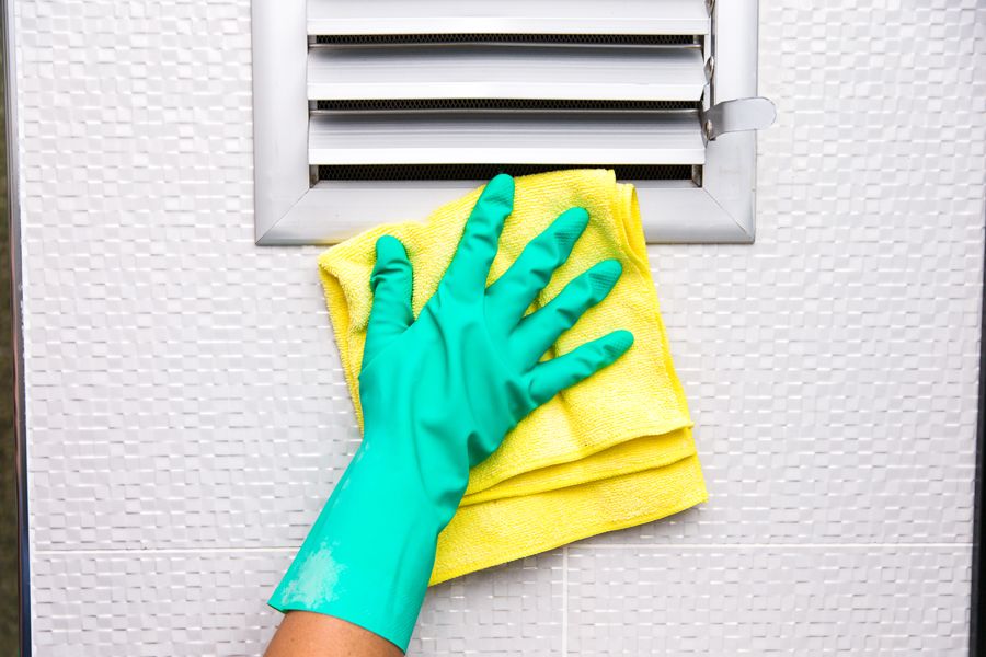 Image of someone cleaning air duct in green gloves. Air Duct Cleaning.